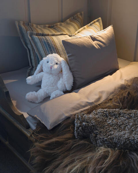 Underetasjen i køyesengen er gjort klar til en liten sovende gjest, med mykt satengsengetøy fra Norsk Dun i nydelig beige farge. 